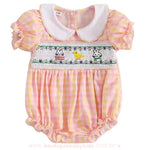 Apresentação frontal do body bebê, destacando o bordado smock com temática de Páscoa e detalhes encantadores para um look especial e sofisticado.