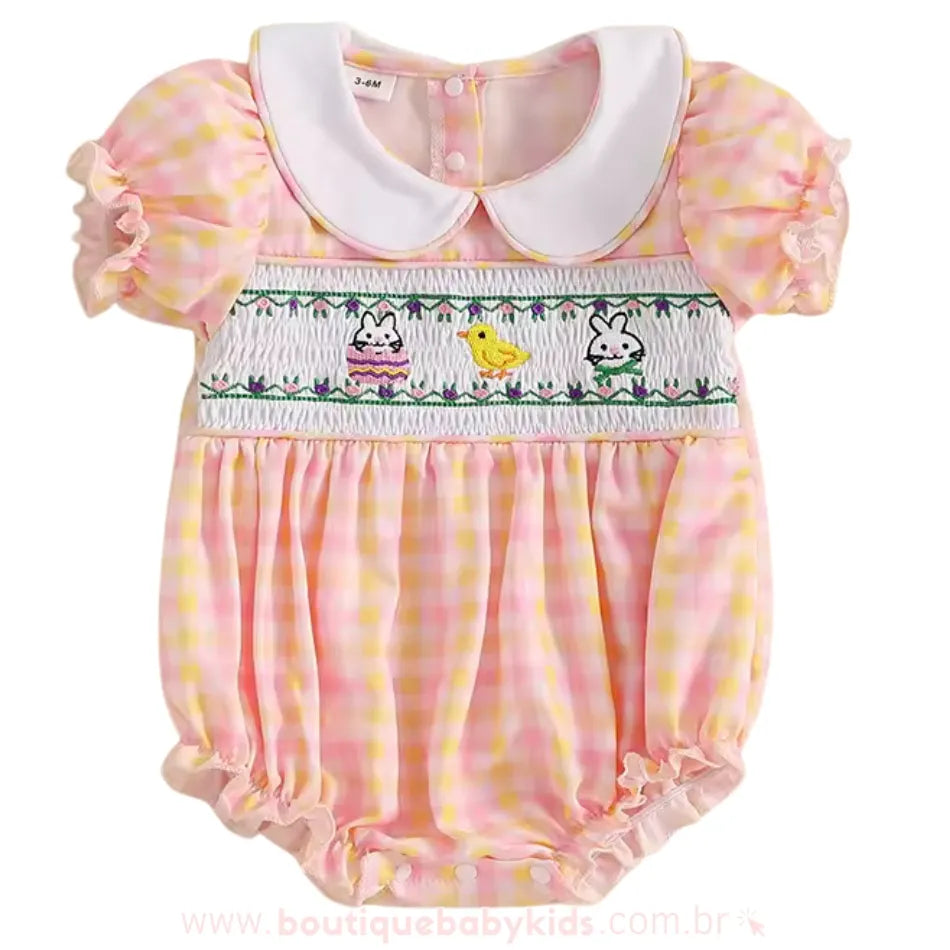 Apresentação frontal do body bebê, destacando o bordado smock com temática de Páscoa e detalhes encantadores para um look especial e sofisticado.