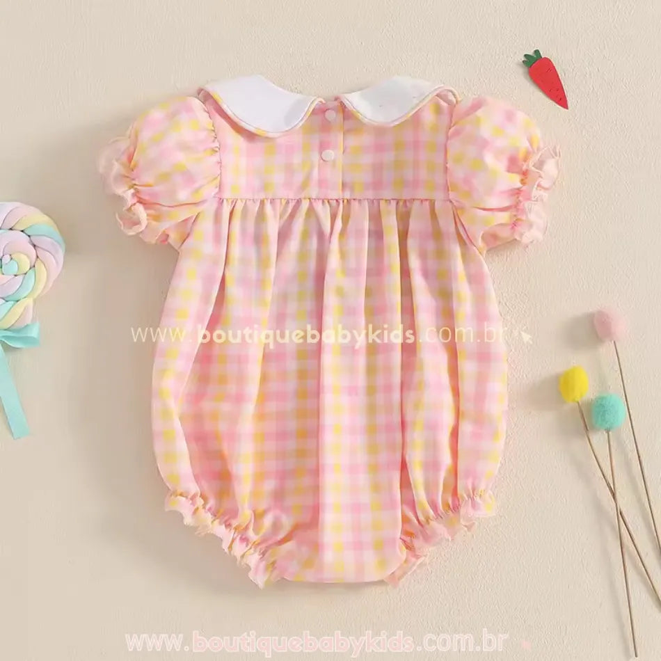 Vista traseira do body bebê, mostrando as manguinhas bufantes, tecido leve xadrez rosa e amarelo, e fechamento delicado com botões.