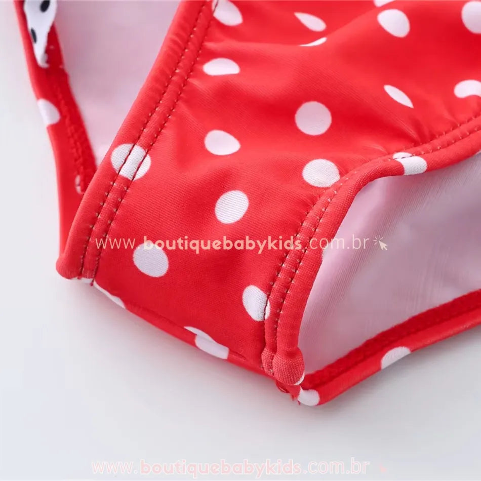 Detalhe da costura e acabamento da parte inferior do maiô infantil engana mamãe Joaninha, com estampa de bolinhas brancas sobre fundo vermelho.