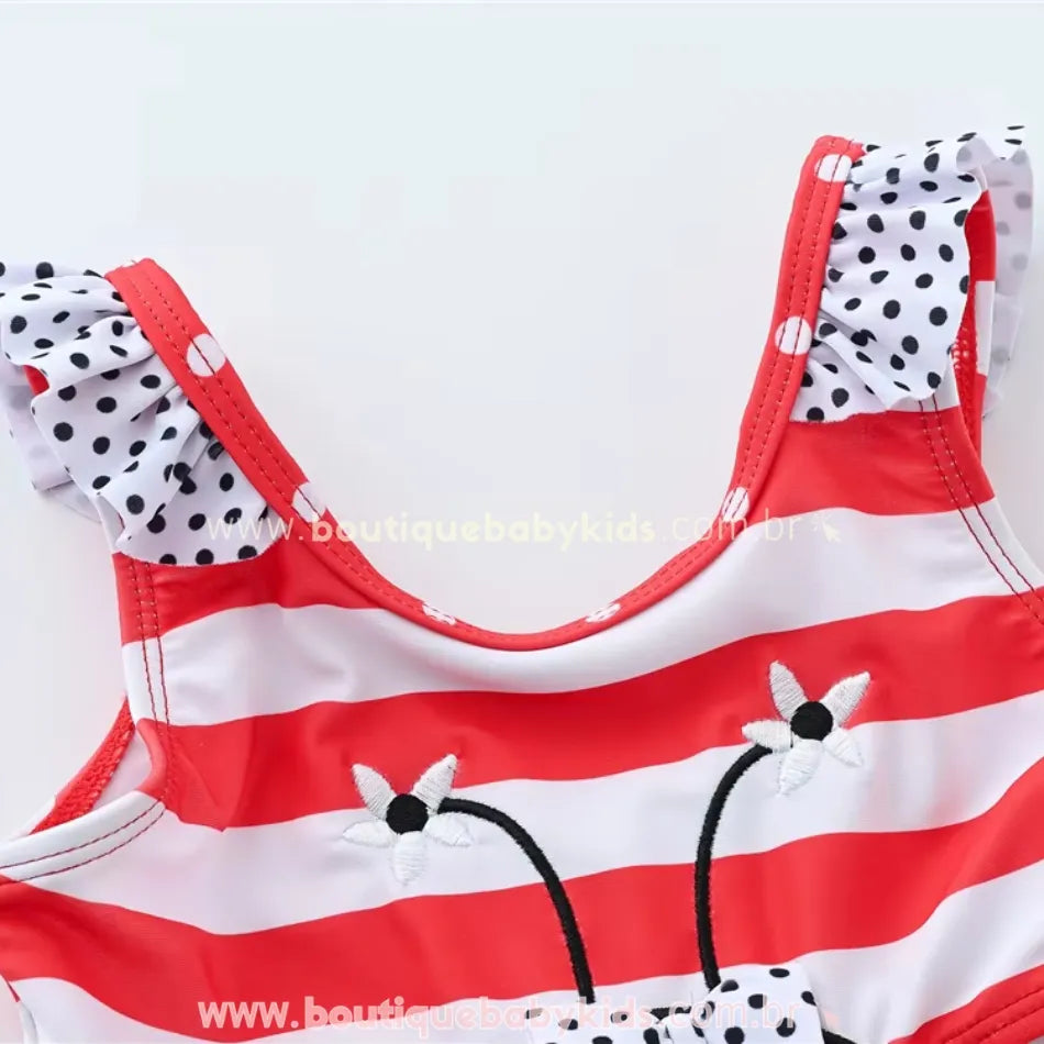 Parte superior do maiô infantil engana mamãe Joaninha, mostrando as alças com babados em estampa de bolinhas e a delicada aplicação floral bordada.