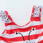 Parte superior do maiô infantil engana mamãe Joaninha, mostrando as alças com babados em estampa de bolinhas e a delicada aplicação floral bordada.