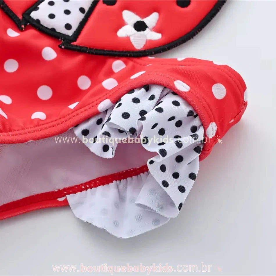 Vista lateral do maiô infantil engana mamãe Joaninha, destacando os babadinhos com estampa poá preta e branca e a aplicação da joaninha bordada no centro.