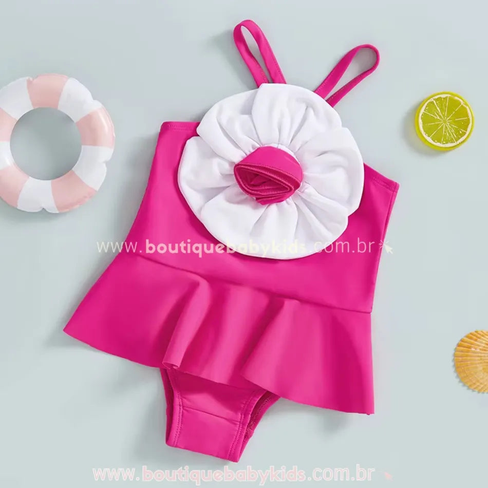 Maiô rosa vibrante com aplicação de flor volumosa na parte frontal, com fundo temático de verão.