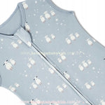 Close-up do tecido azul claro do saco de dormir para bebê, com estampa delicada de carneirinhos brancos e pequenas estrelas. O zíper frontal com proteção no topo também é visível.