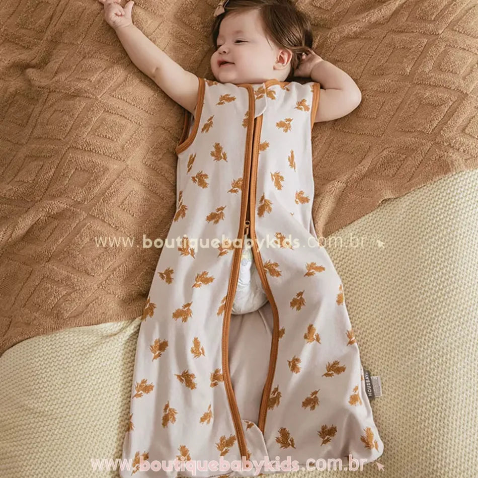 Bebê dormindo tranquilamente no Saco de Dormir Bebê Folhas de Outono, um modelo sem mangas que mantém o bebê aquecido e confortável sem a necessidade de cobertores.