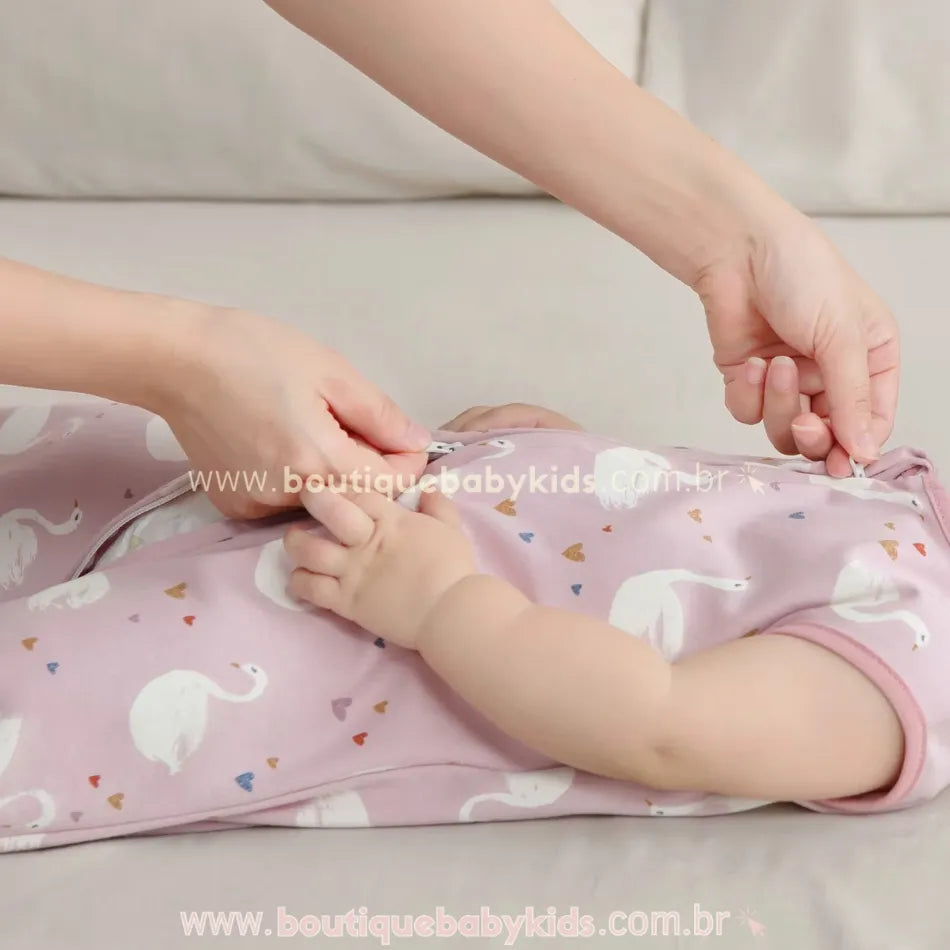 Saco de dormir para bebê com zíper duplo, facilitando a troca de fraldas. Modelo rosa com estampa delicada de cisnes e corações.