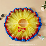 Saia infantil Branca de Neve aberta em formato circular, com tule volumoso amarelo e detalhes de fita de cetim azul e vermelho, além de laço decorativo.