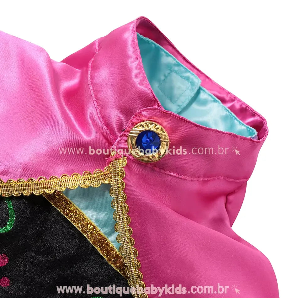 Gola alta com detalhe dourado e pedra azul no fechamento, junto à capa rosa brilhante fixa ao vestido.