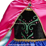 Capa rosa brilhante fixada ao vestido, com bordas douradas e acabamento sofisticado.