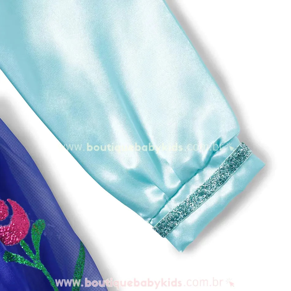 Detalhe da manga longa em cetim azul-claro, com punho elástico e fita brilhante decorativa.