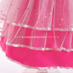 Detalhe do tule rosa do vestido infantil Barbie Glamour, com aplicações douradas em formato de estrela e barra finalizada com fita de cetim.