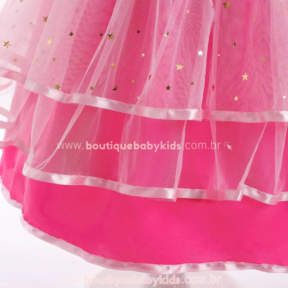Detalhe do tule rosa do vestido infantil Barbie Glamour, com aplicações douradas em formato de estrela e barra finalizada com fita de cetim.