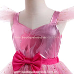 Close do laço rosa vibrante na cintura do vestido Barbie Glamour, destacando a silhueta da Barbie no tecido brilhante do corpete.