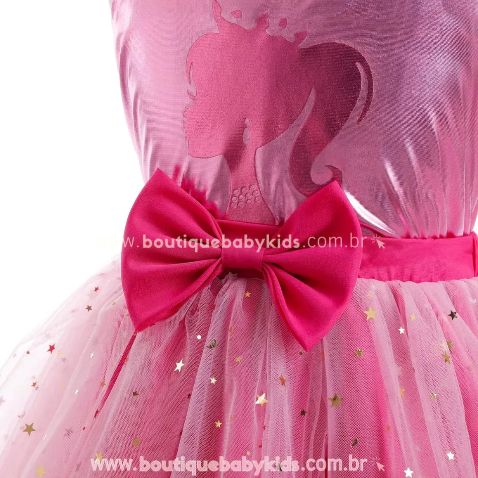 Parte superior do vestido infantil temático da Barbie, com tecido metalizado rosa e estampa de perfil da boneca, além de ombreiras delicadas em tule com estrelas douradas.