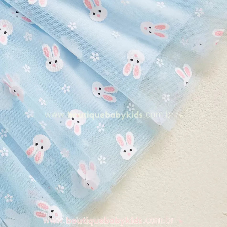 Detalhe da barra do vestido azul, exibindo a fluidez do tecido e a transparência sutil do tule, criando um efeito leve e elegante. 