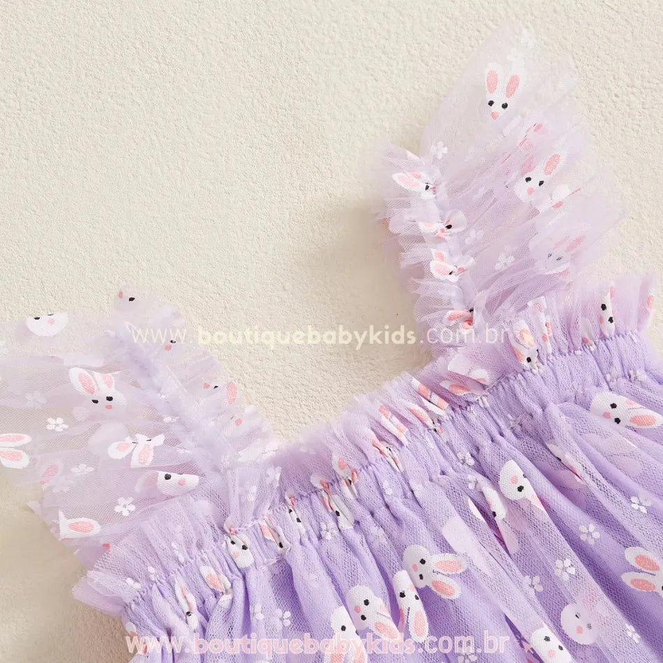 Parte superior do vestido lilás, com alças franzidas e tule estampado de coelhinhos e flores brancas, trazendo um visual delicado e encantador para ocasiões especiais. 