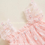 Detalhe do ombro do vestido rosa, com alças de tule franzido estampadas com coelhinhos brancos e pequenas flores brancas, trazendo um toque delicado e encantador à peça. 