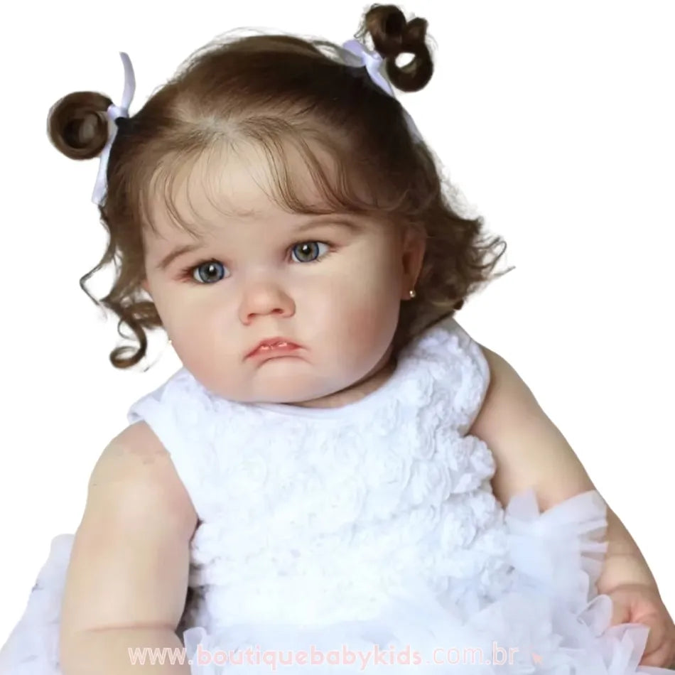Foto da Boneca Bebê Reborn Camila, destacando os detalhes do vestido branco e os traços realistas do rosto.