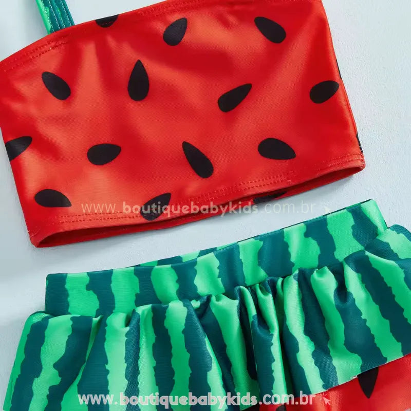 Detalhe aproximado do tecido do Biquíni Melancia Summer, mostrando a textura da estampa de sementes no top vermelho e o contraste com o babado verde listrado da calcinha.