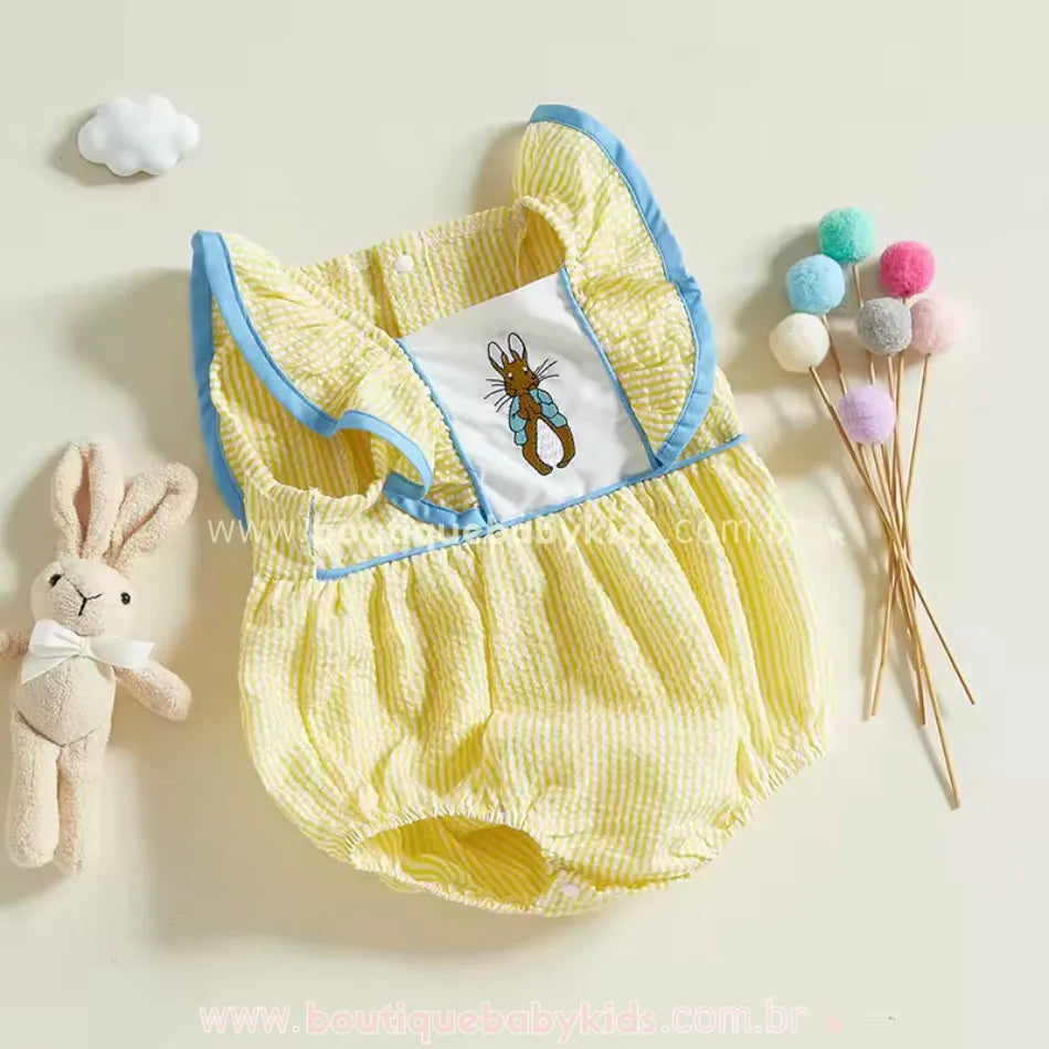 Body amarelo listrado para bebê, com fechamento por botões de pressão na parte inferior e bordado delicado de coelho, acompanhado de decoração em tons pastéis.