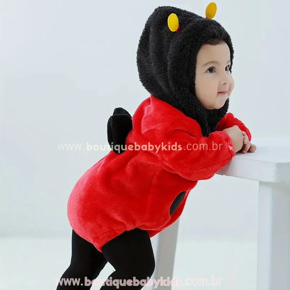 Bebê de perfil usando Body Fantasia Joaninha com capuz e anteninhas em pelúcia macia