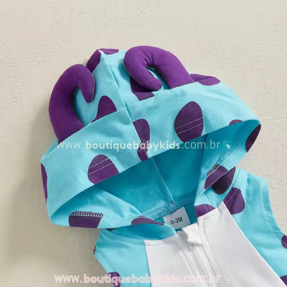 Capuz do body bebê fantasia Monstrinho Sulley, com chifrinhos roxos acolchoados e estampa azul com manchas roxas.
