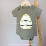 Body infantil manga curta na cor verde militar com estampa frontal simulando a barriga de uma Tartaruga Ninja.
