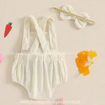 Vista traseira do body bebê jardineira na cor creme, destacando as alças cruzadas ajustáveis e a faixa de cabelo combinando, com detalhe em elástico dourado. 