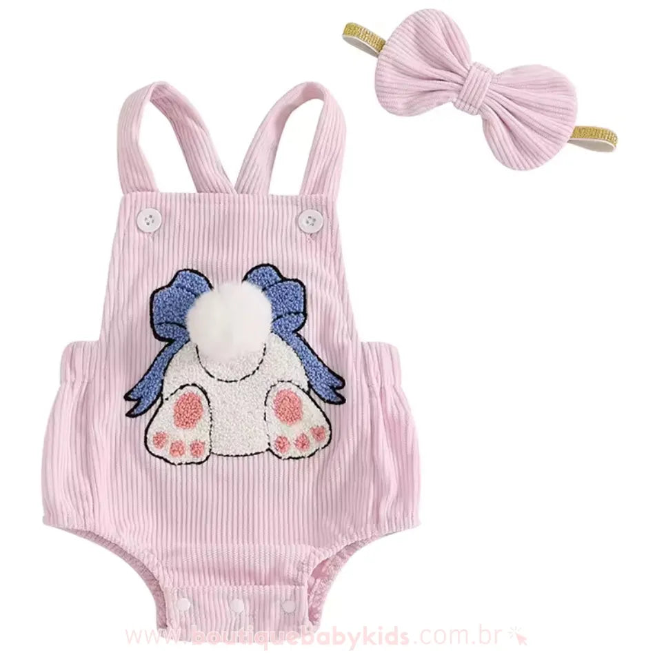 Body bebê jardineira cor-de-rosa com estampa de coelhinha bordada, detalhes em plush e rabinho de pompom branco. Acompanha uma faixa de cabelo combinando. 