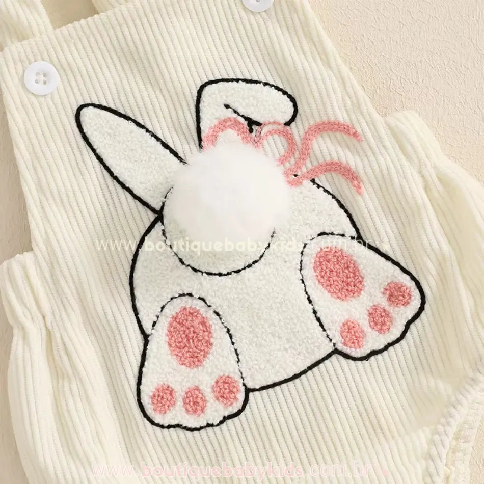 Close do bordado da coelhinha na parte frontal do body, com textura aveludada, orelhinha dobrada e pompom macio representando o rabinho. 