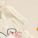 Detalhe das alças do body bebê jardineira, ajustáveis com botões brancos. 