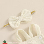 Faixa de cabelo creme com laço estruturado e elástico dourado combinando com a jardineira. 