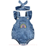 Body bebê jardineira jeans com bordado de arco-íris no bolso frontal, acompanhado por uma faixa de cabelo combinando.
