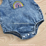 Bordado de arco-íris em cores vibrantes no bolso frontal do body jardineira, proporcionando um toque lúdico à peça.