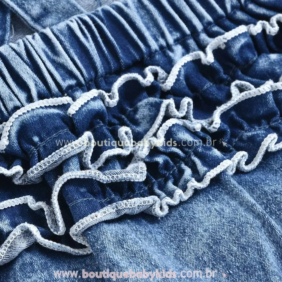 Fechamento inferior com botões de pressão no body jardineira jeans, facilitando a troca de fraldas.