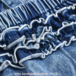 Fechamento inferior com botões de pressão no body jardineira jeans, facilitando a troca de fraldas.