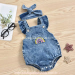 Conjunto de body jardineira jeans com faixa de cabelo em um fundo de madeira, destacando os detalhes delicados da peça.