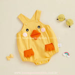 Body bebê amarelo com alças cruzadas e rosto de patinho estampado, com bico em tecido e bolsos em formato de patinhas laranja – Boutique Baby Kids.