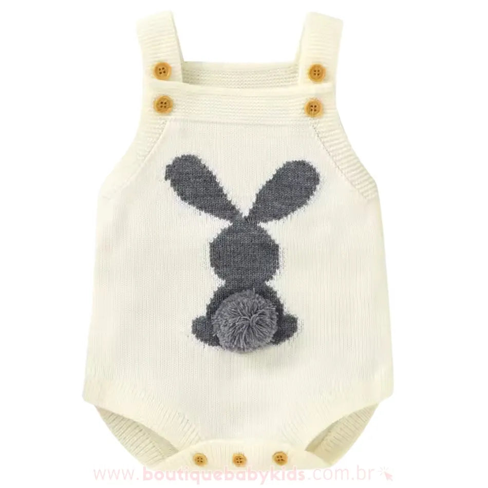 Body bebê jardineira de tricot na cor branco, com um coelhinho branco na parte traseira e rabinho de pompom, alças com botões ajustáveis. 