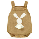 Body bebê jardineira de tricot na cor caramelo, com um coelhinho branco na parte traseira e rabinho de pompom, alças com botões ajustáveis. 