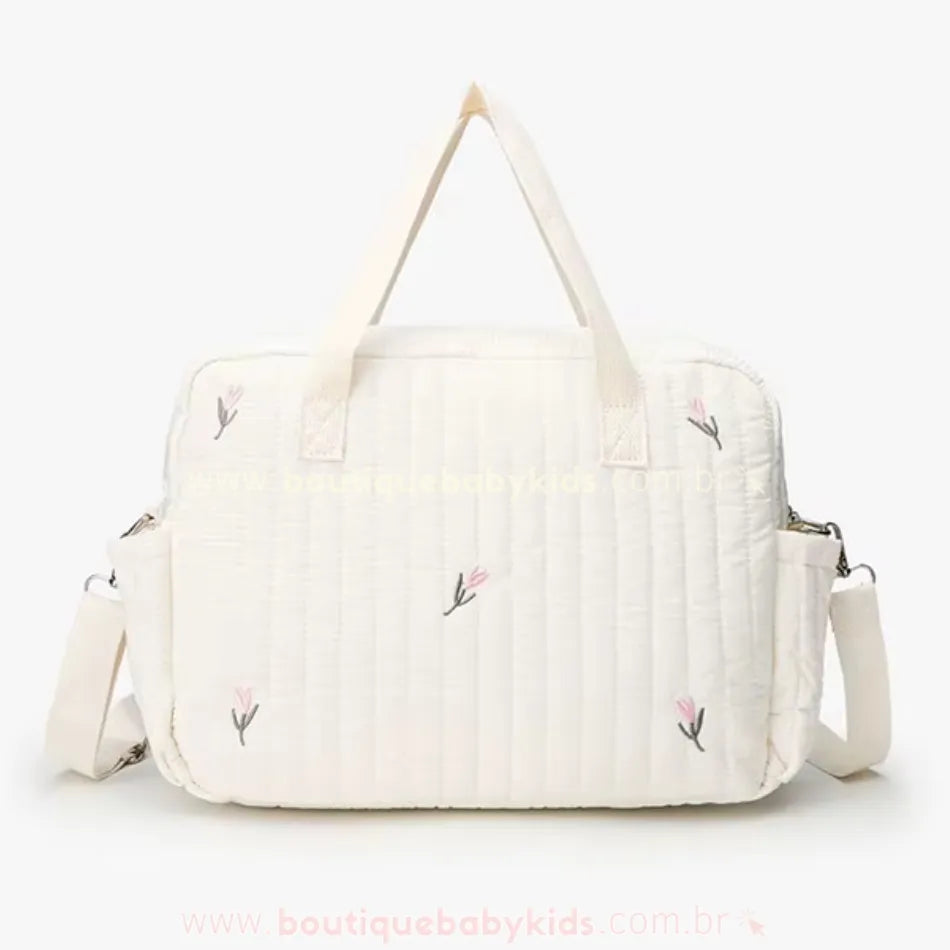 Vista traseira da bolsa maternidade Delicadeza Floral, destacando o design minimalista com bordado floral, alça de ombro ajustável e laterais com presilhas metálicas para encaixe no carrinho do bebê.
