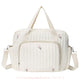 Bolsa maternidade delicada em tom off-white com bordado floral minimalista em rosa e verde. Modelo estruturado com alças duplas e um bolso frontal espaçoso com zíper.