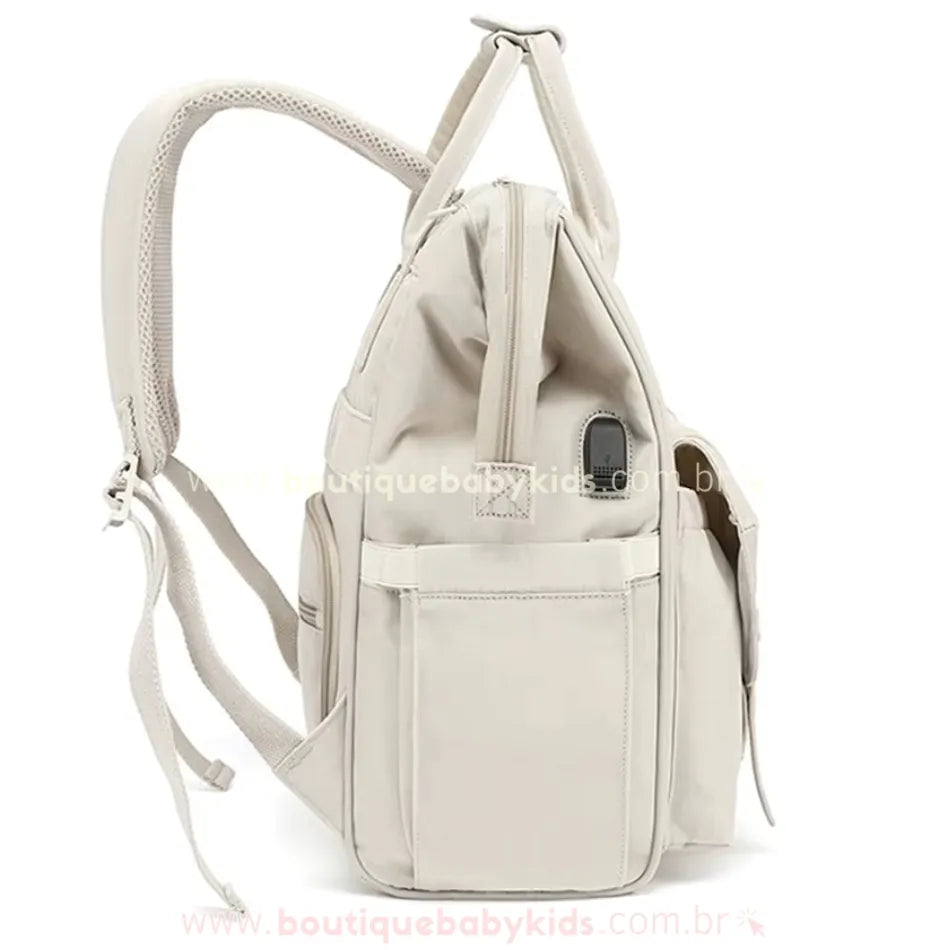 Visão lateral da bolsa mochila maternidade elegance, destacando os bolsos externos e a porta USB embutida para carregamento de dispositivos.