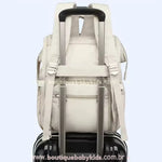 Bolsa Mochila Maternidade Elegance acoplada a uma mala de viagem, mostrando a faixa para encaixe na alça retrátil.