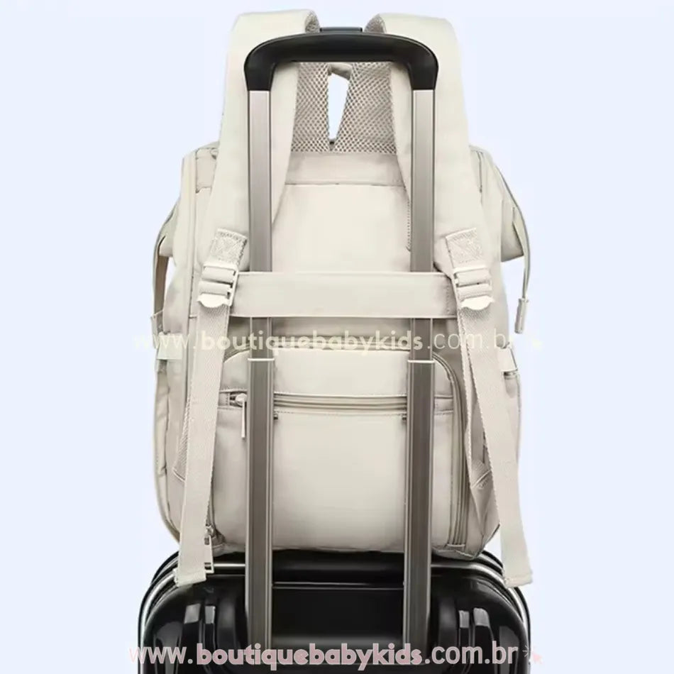 Bolsa Mochila Maternidade Elegance acoplada a uma mala de viagem, mostrando a faixa para encaixe na alça retrátil.