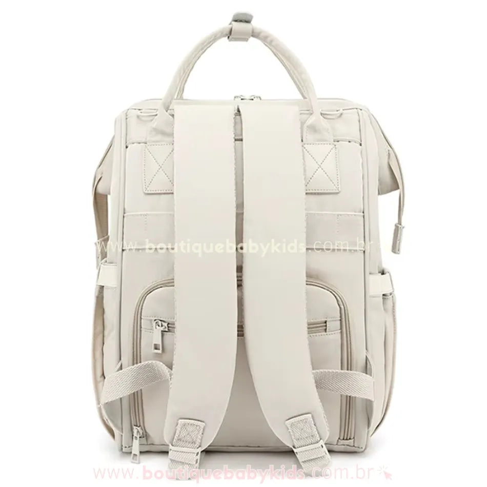 Parte traseira da bolsa mochila maternidade elegance na cor bege, evidenciando as alças ajustáveis e o compartimento com zíper.