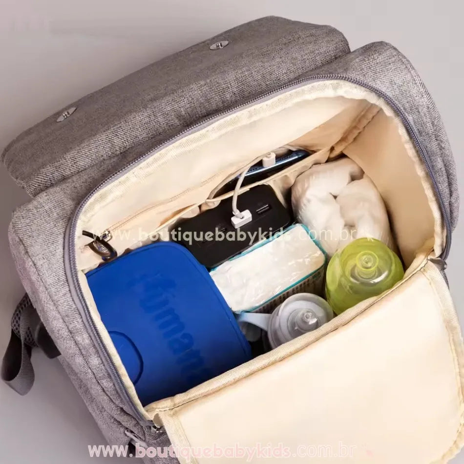 Interior espaçoso da mochila maternidade Insular Travel, contendo fraldas, mamadeiras e acessórios organizados, demonstrando a grande capacidade de armazenamento.