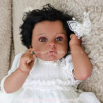 Close-up do rosto da Boneca Bebê Reborn Cecília negra, mostrando detalhes realistas da pele, olhos castanhos brilhantes, cabelos cacheados pretos e colar de pérolas delicado.