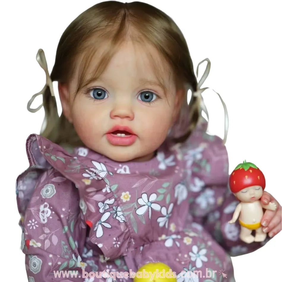 Close da Boneca Bebê Reborn Julia com vestido floral lilás, olhos azuis marcantes e brinquedo de morango nas mãos.